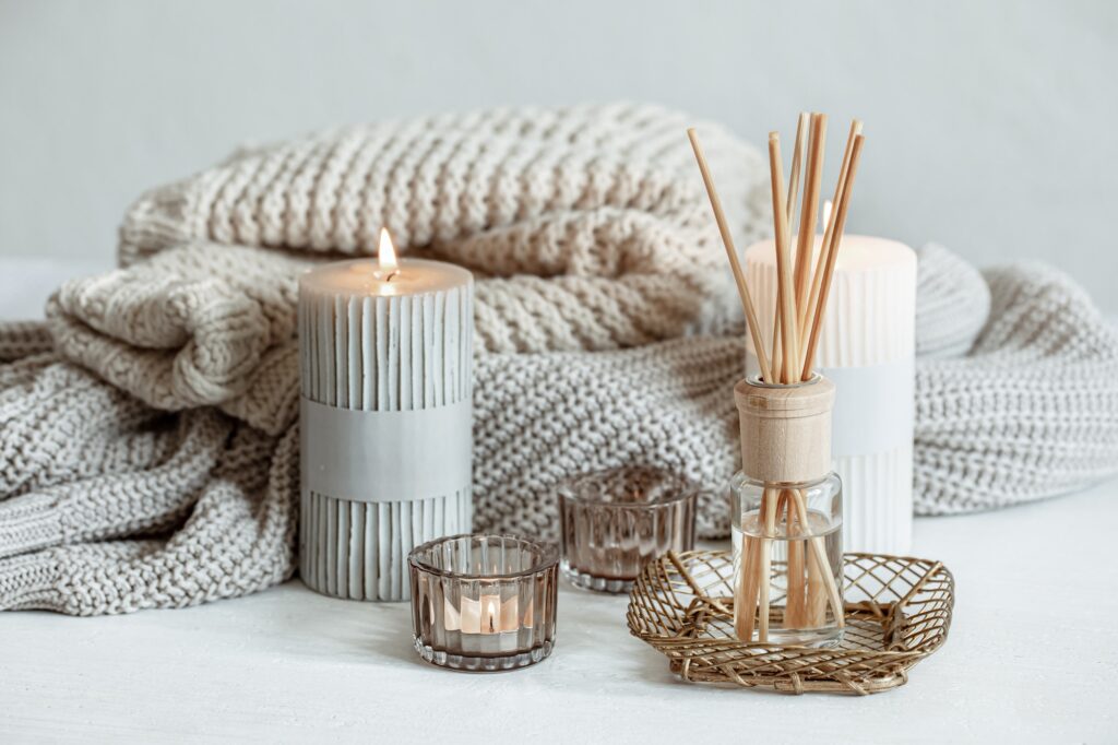 cozy home composition with candles aroma sticks and a knitted element